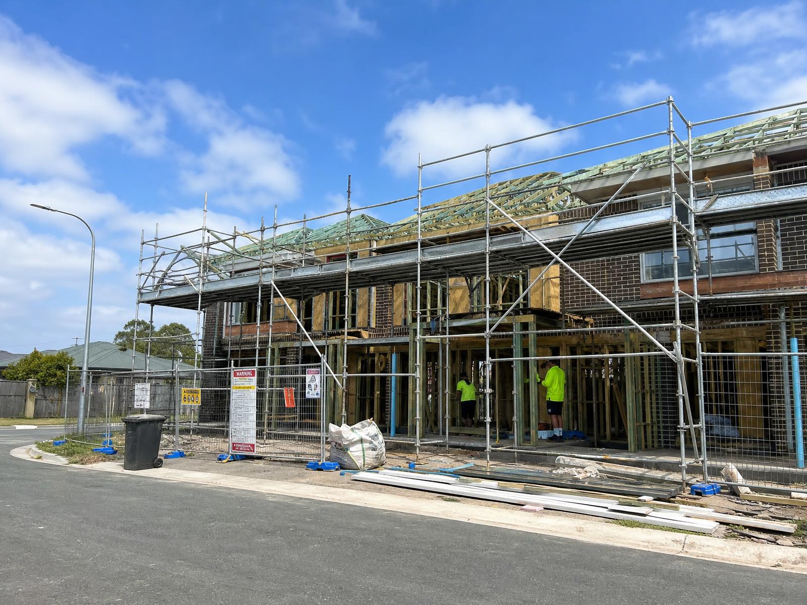 Australian low-rise residential townhouses under construction with scaffolding and roof trusses